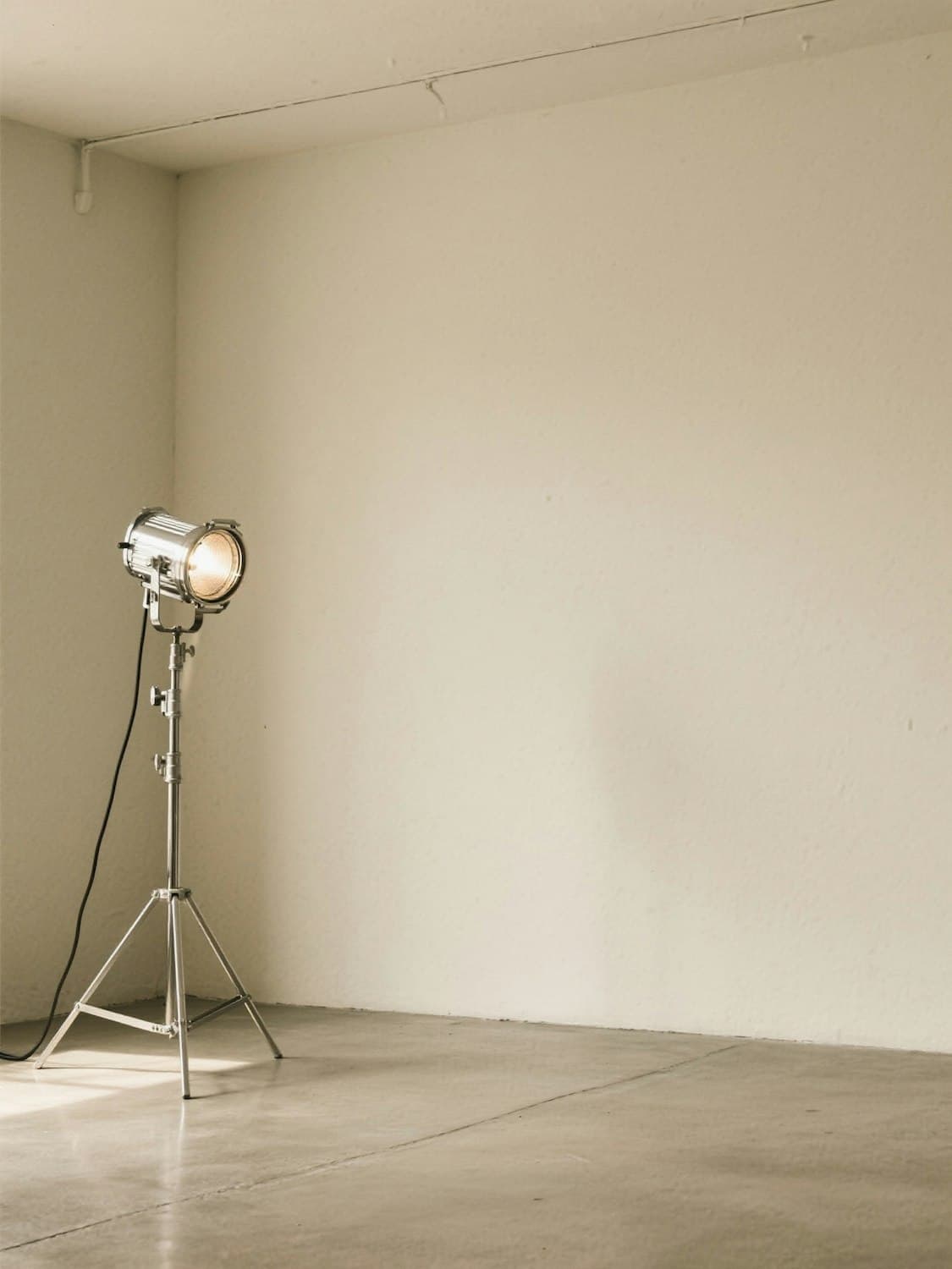 A single film lamp on a stand in an empty room.